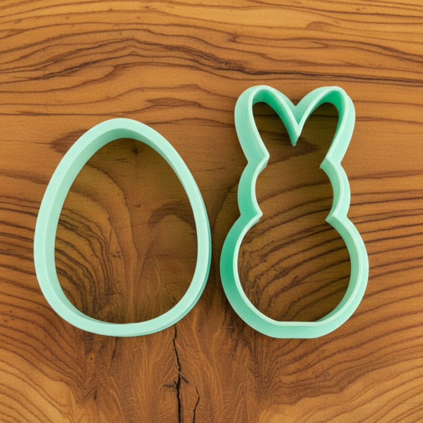 Two cookie cutters, one in the shape of a bunny and the other in shape of an egg
